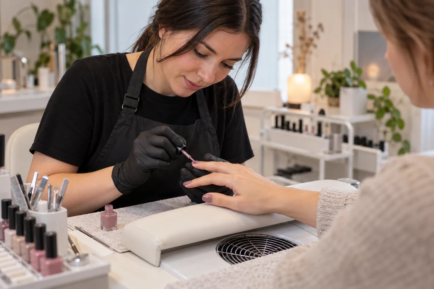 Una profesional aplica esmalte en una mesa de uñas.
